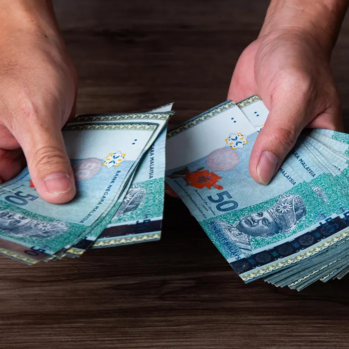 a man counting Malaysian Ringgit currency notes