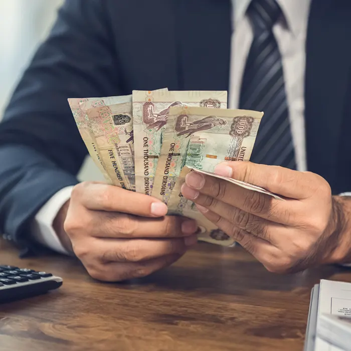 a man in suit counting dirham currency notes